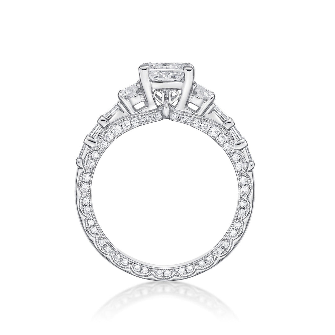 The Amelia princess cut engagement ring features Round brilliant cut diamonds grain set into each side, finished with millgrain detailing in a scalloped design